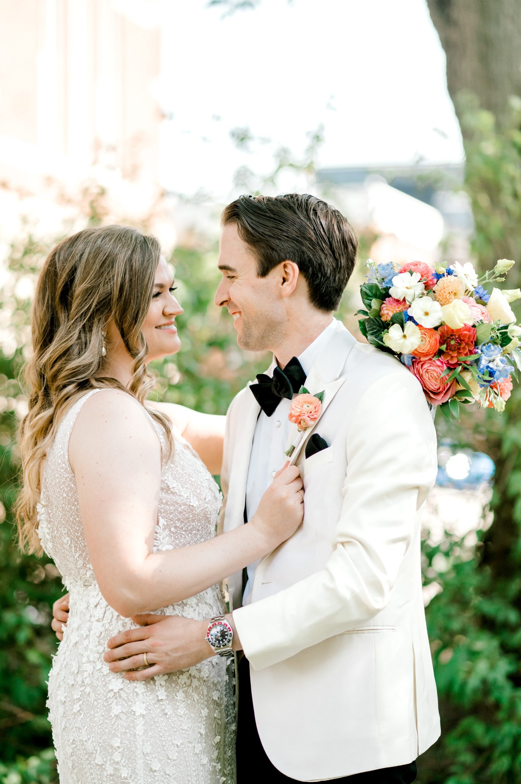 bride and groom smiling looking at each other with colorful flowers