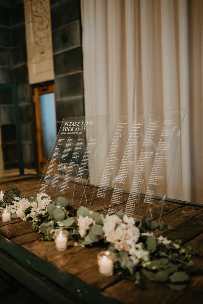 modern seating chart display on clear acrylic signs with greenery and floral accents