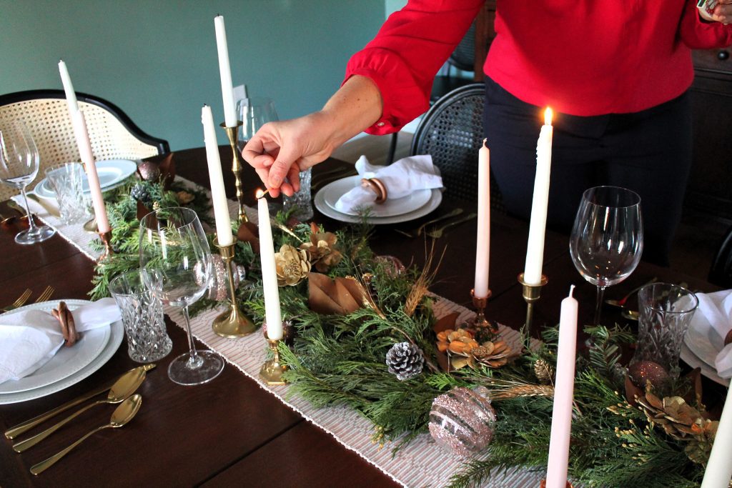 lighting the taper candles on a Christmas dinner dining table