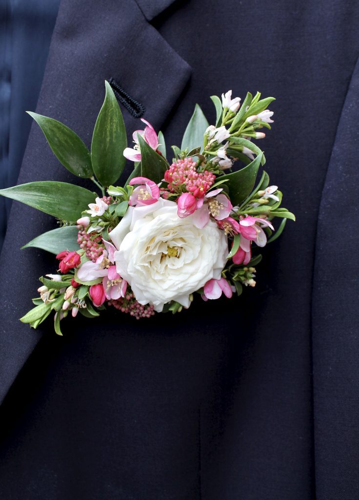white pink and greenery fresh flower pocket square on navy blue suit jacket